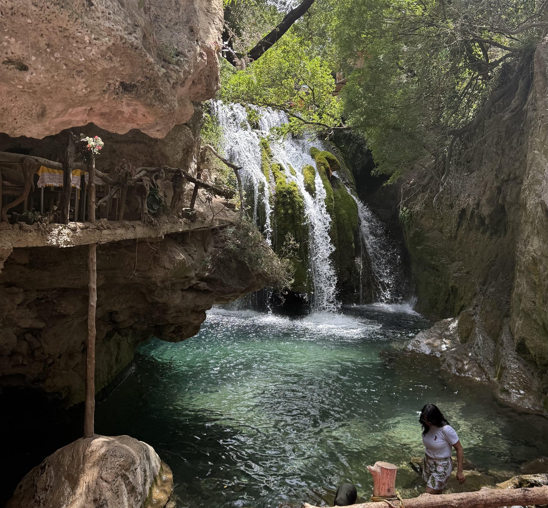 A clear turquoise pool beneath the moss-covered Akchour waterfall