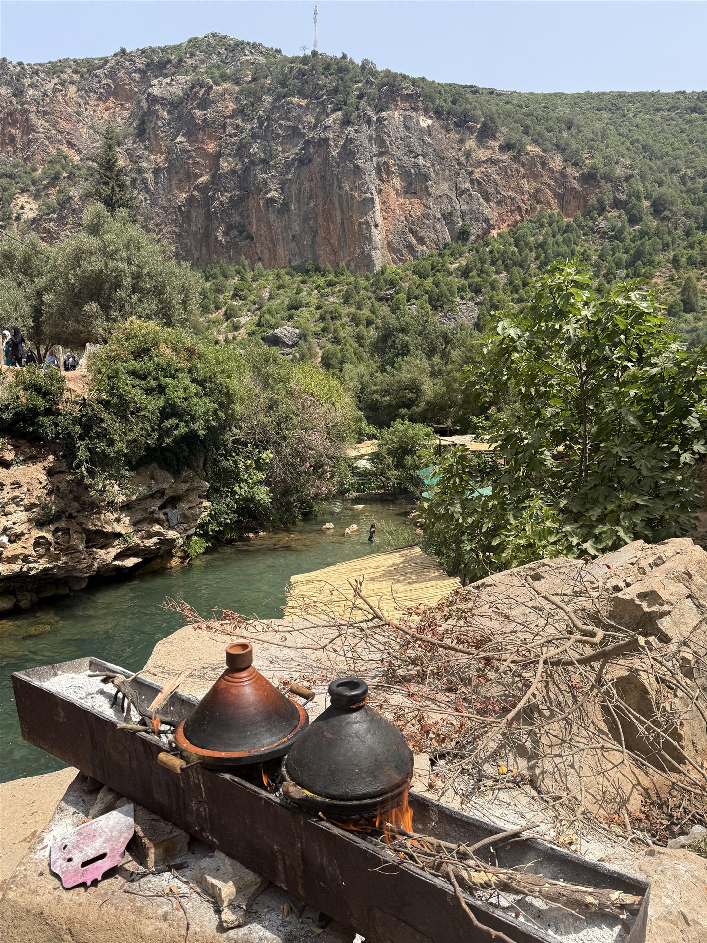 Traditional Moroccan tagines cooking over a wood fire beside the river
